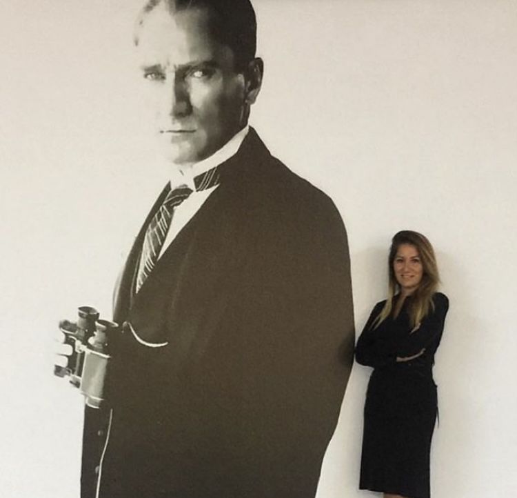 Sema Gül Bayoğlu, büyük bir Atatürk fotoğrafının yanında